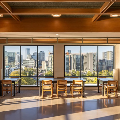 tables and chairs next to large windows with city views