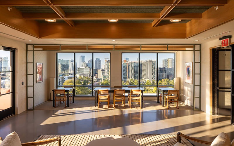 tables and chairs next to large windows with city views