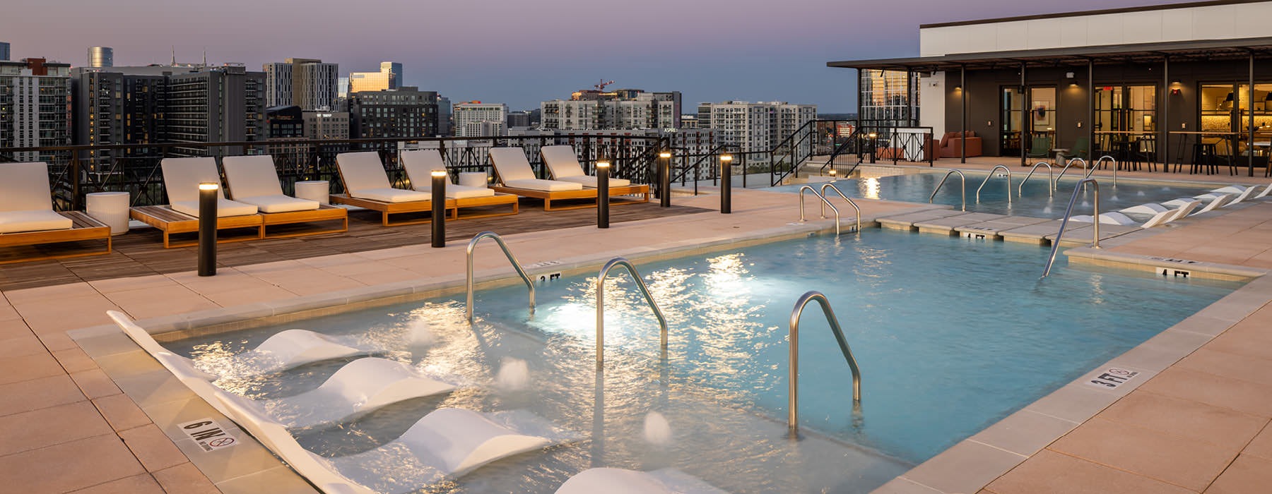 rooftop pool at night with lights and city views